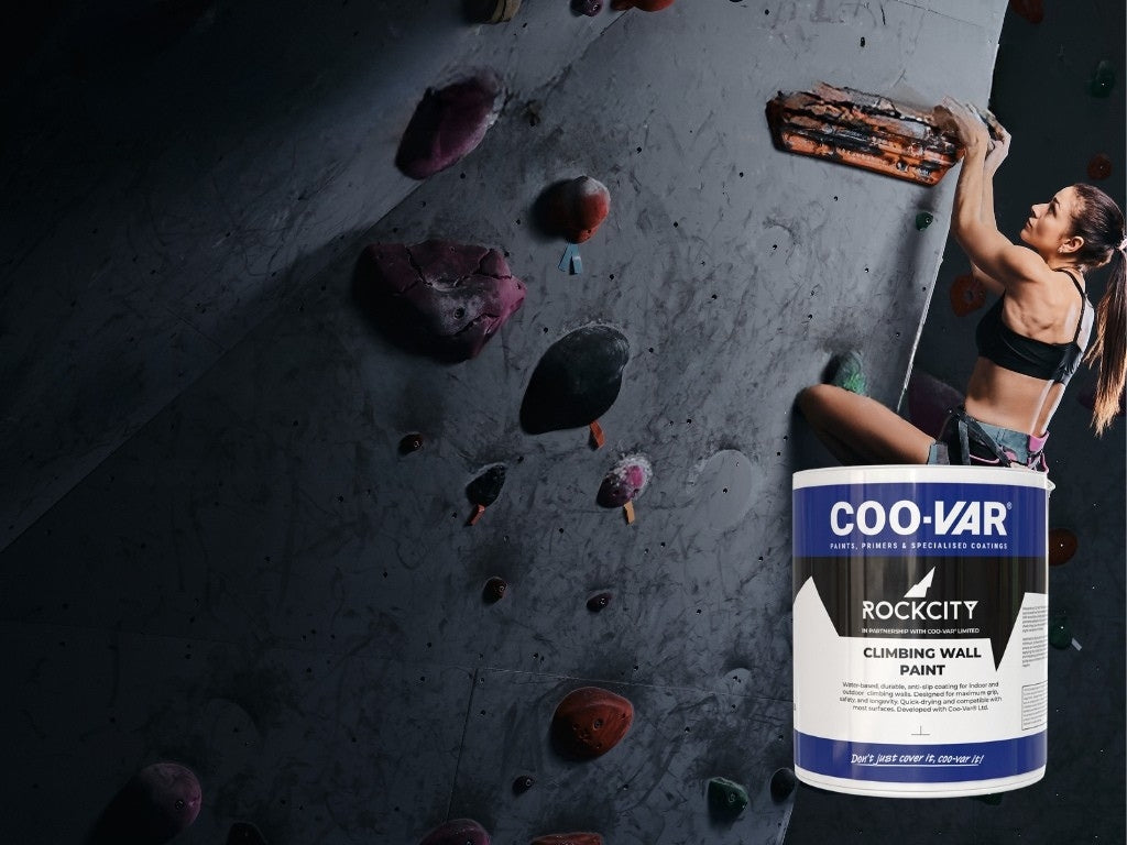 Person climbing on a rock wall painted with Rockcity x COO-VAR paint and can in the foreground